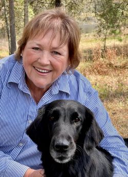 Photo of Dr. Mary Smith with her Flat-Coated Retriever Kenley in the woods