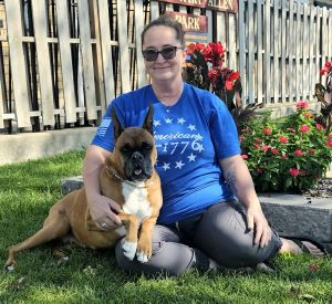 Julie HIggins and her Boxer, Sophia, sitting in the yard on a sunny day